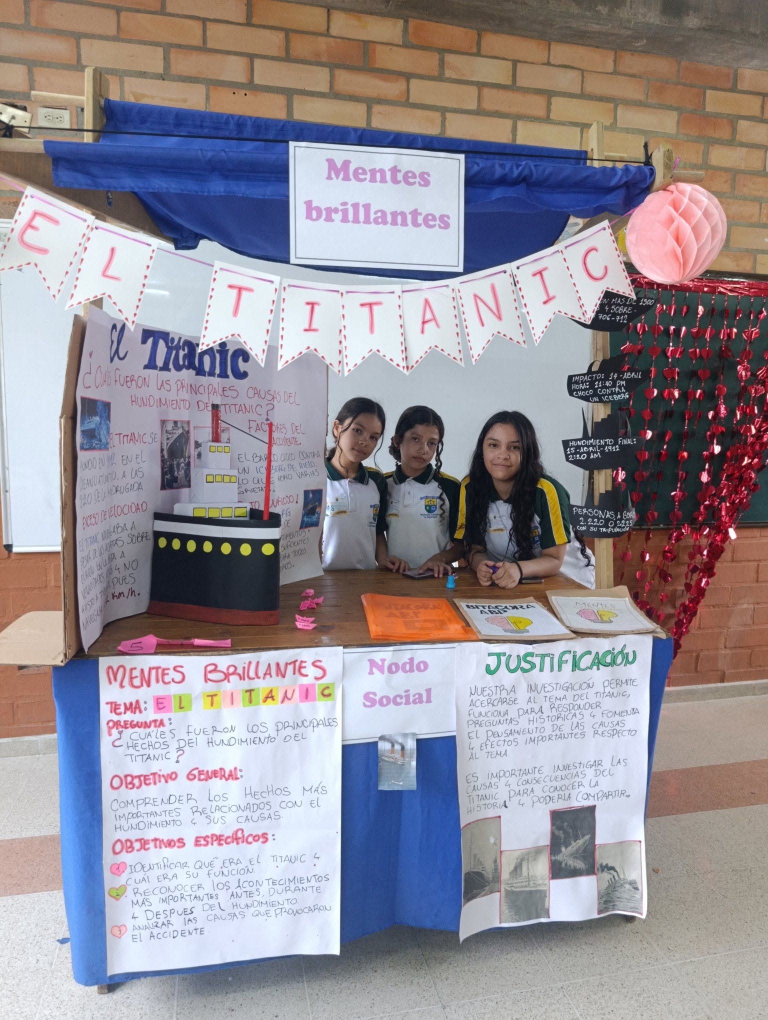 tres estudiantes están en su estante exponiendo el proyecto